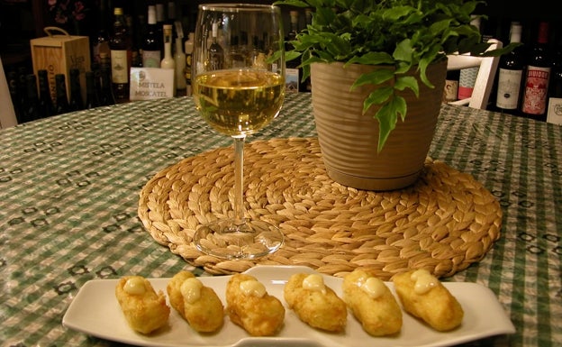 Imagen principal - Arriba, albóndigas de bacalao acompañada de vino blanco de la vinoteca Vins i més. Abajo a la izquierda, tabla de jamón ibérico y copa de tinto. Abajo a la derecha, tosta de salmón ahumado con vino rosado y blanco del local.