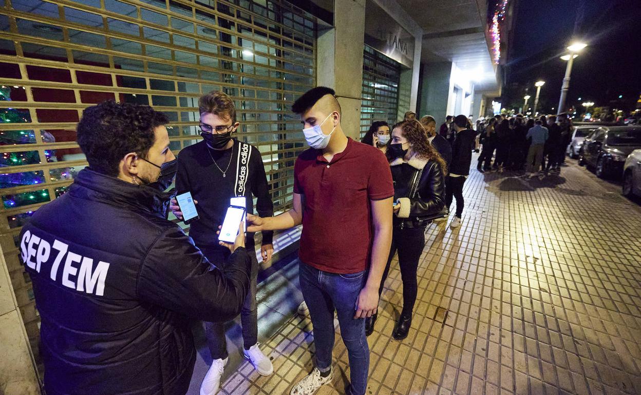 Un joven muestra su pasaporte Covid antes de entrar a un local en Valencia.