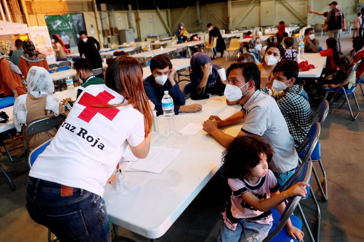 Una voluntaria habla con una familia afgana tras su llegada a España. AFP