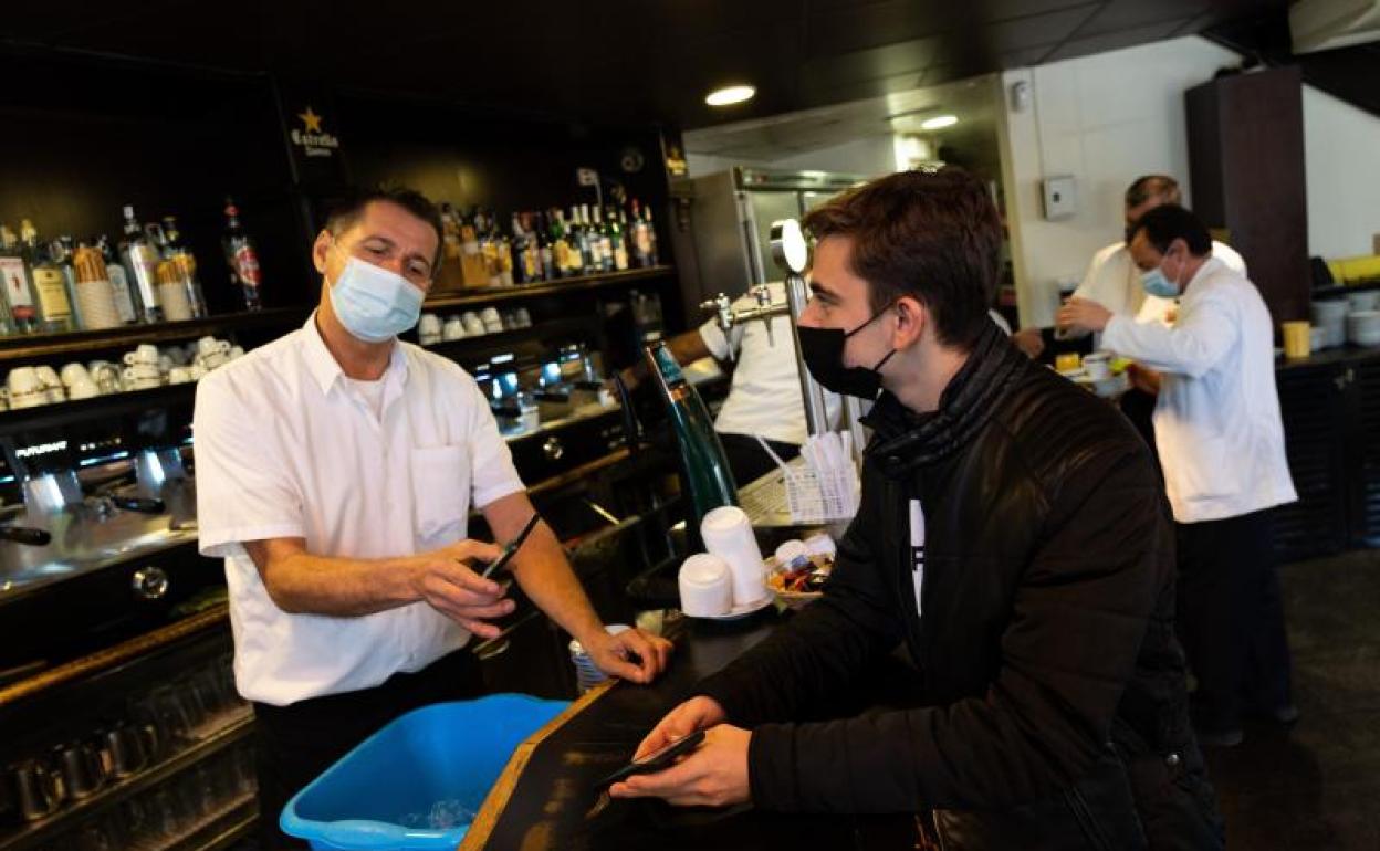 Un cliente muestra su pasaporte covid en un bar. 