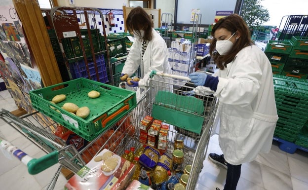 Dos mujeres preparan los lotes de alimentos antes de su reparto. 