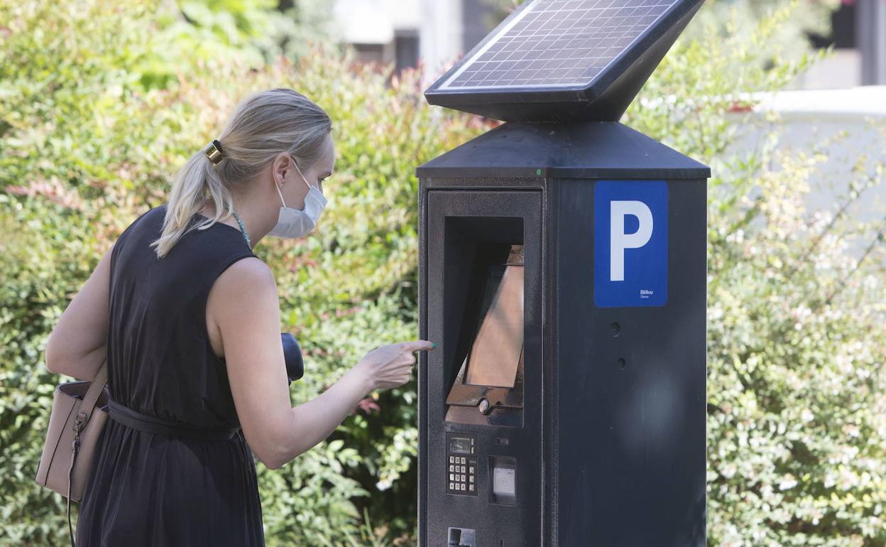 Una mujer usa un parquímetro de la ORA.