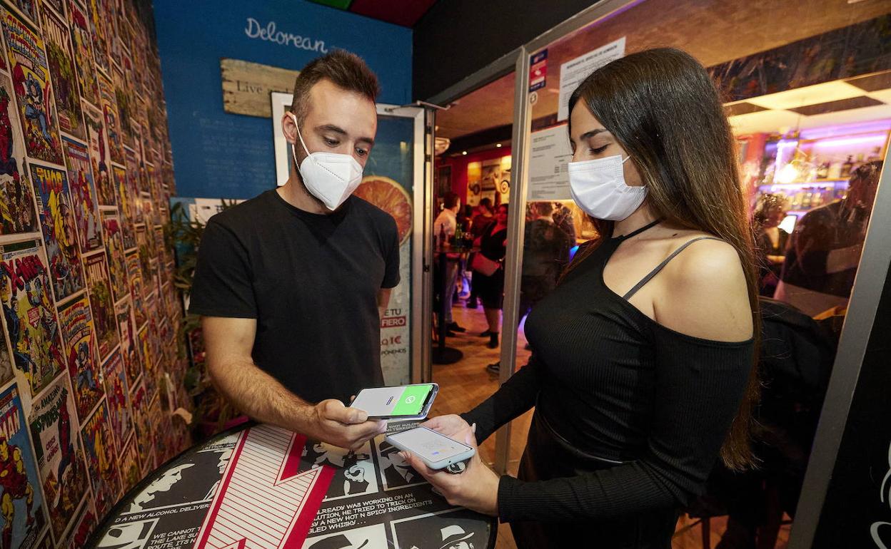 Una joven enseña su pasaporte Covid ante la entrada de un pub en Valencia. 