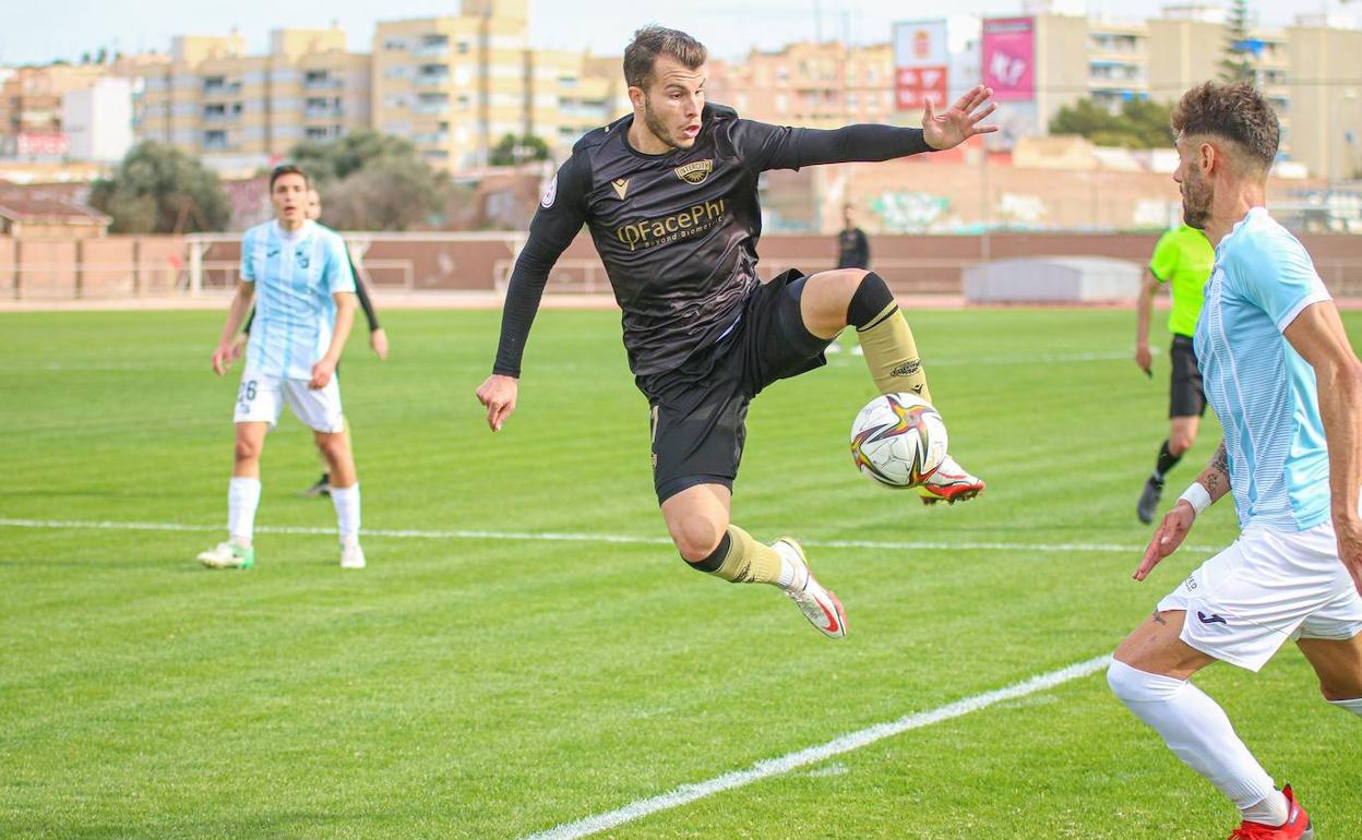 Pol Roigé trata de controlar un balón ante un jugador de La Nucía en el partido de esta mañana en Santa Pola. 