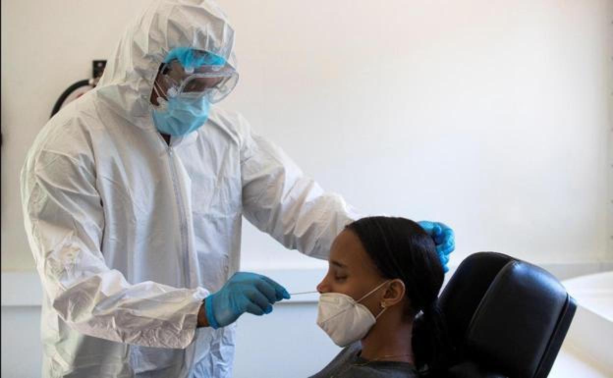 Un sanitario realiza una PCR a una joven. 