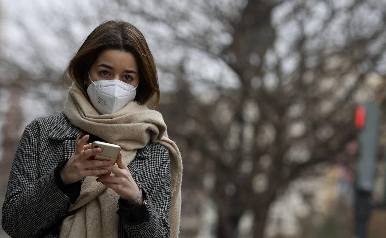 Una joven pasea por Valencia con mascarilla. 