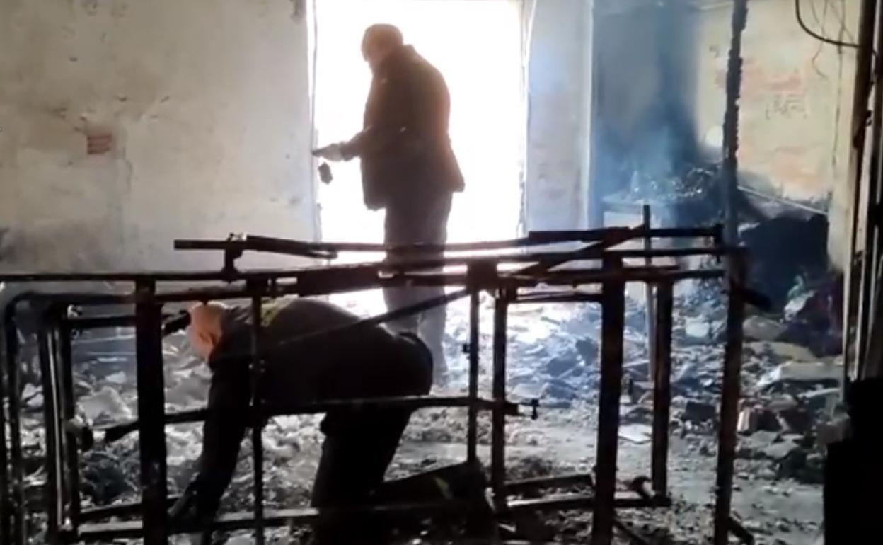 Dos agentes inspeccionan la habitación donde se inició el fuego. 