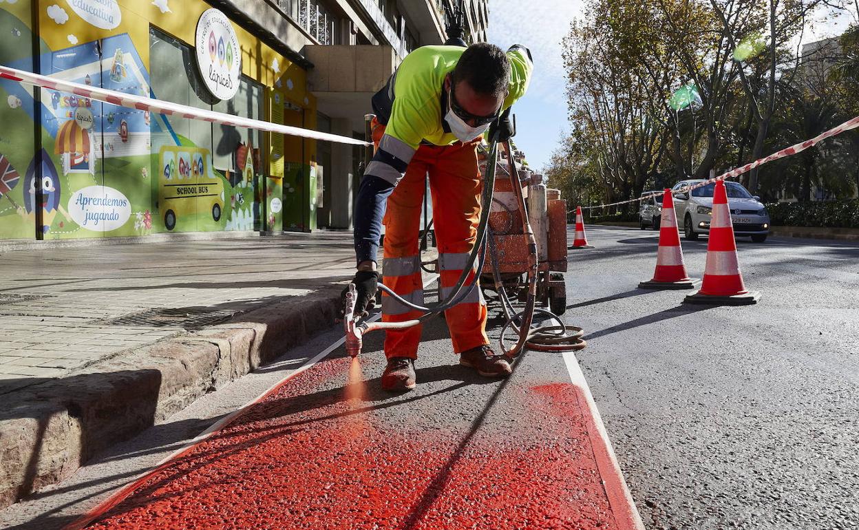 Un operario pinta un carril bici en Valencia.