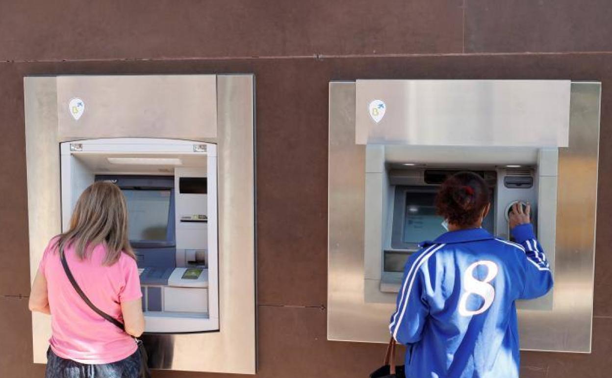 Dos clientes en un cajero automático a pie de calle.