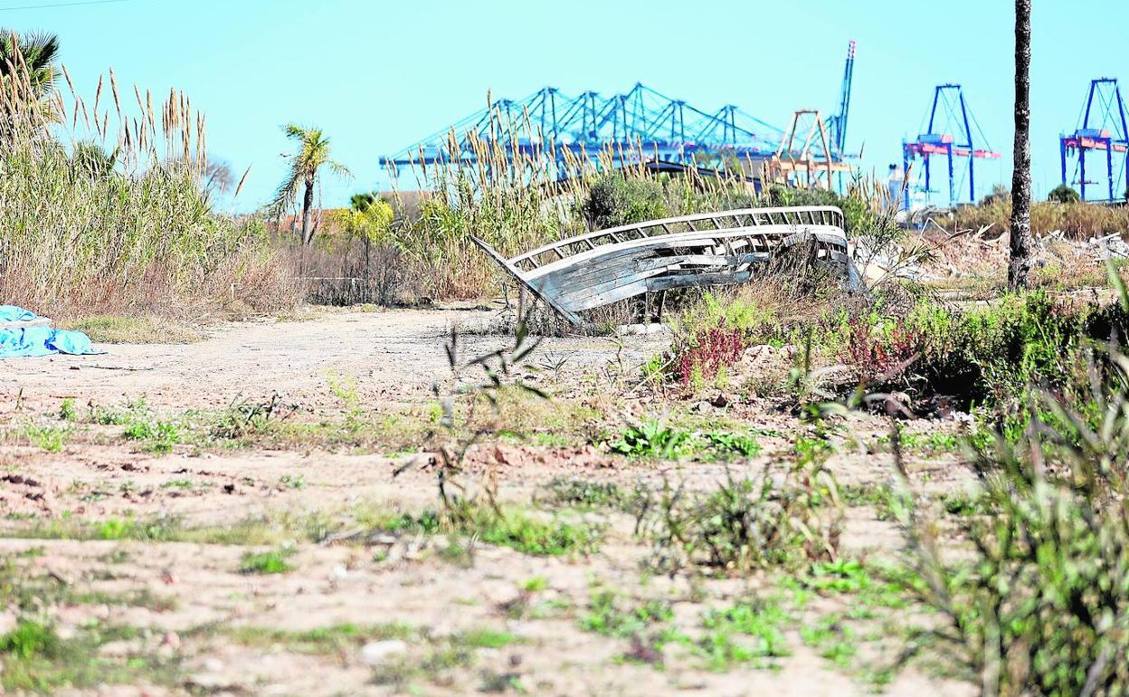 La Punta. Una barca desvencijada, escombros y plásticos en lo que fue un campo cultivado. Al fondo, las grúas del puerto.