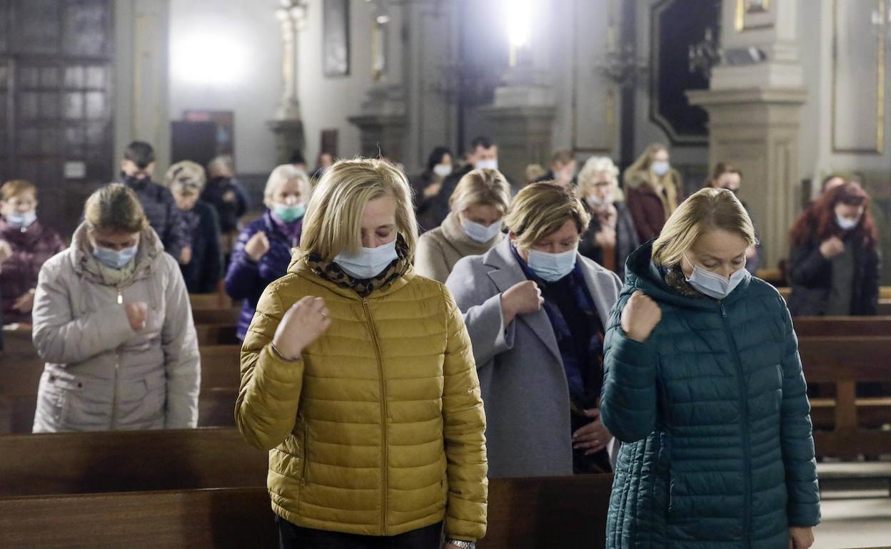 Fieles ucranianos se persignan durante la misa por la paz celebrada este viernes en la iglesia del Pilar en Valencia. 