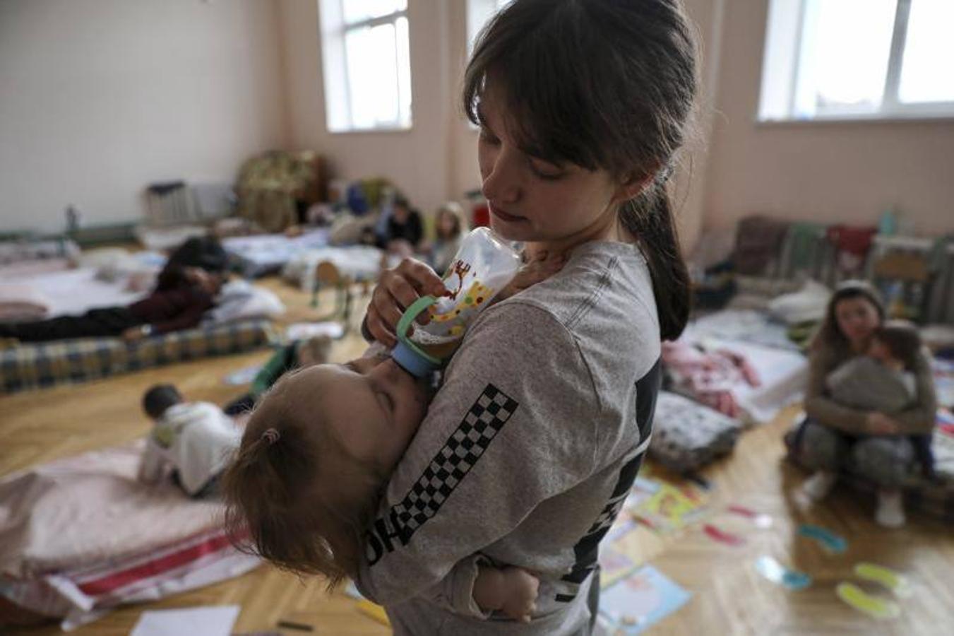 Un madre alimenta a su bebé en un refugio para niños.