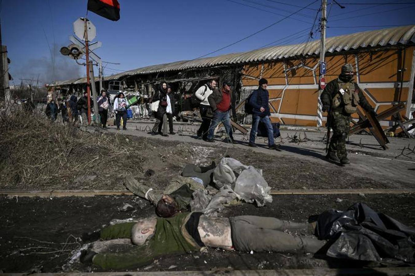 Los residentes pasan junto al cuerpo de un soldado ruso mientras evacuan la ciudad de Irpin, al norte de Kiev.