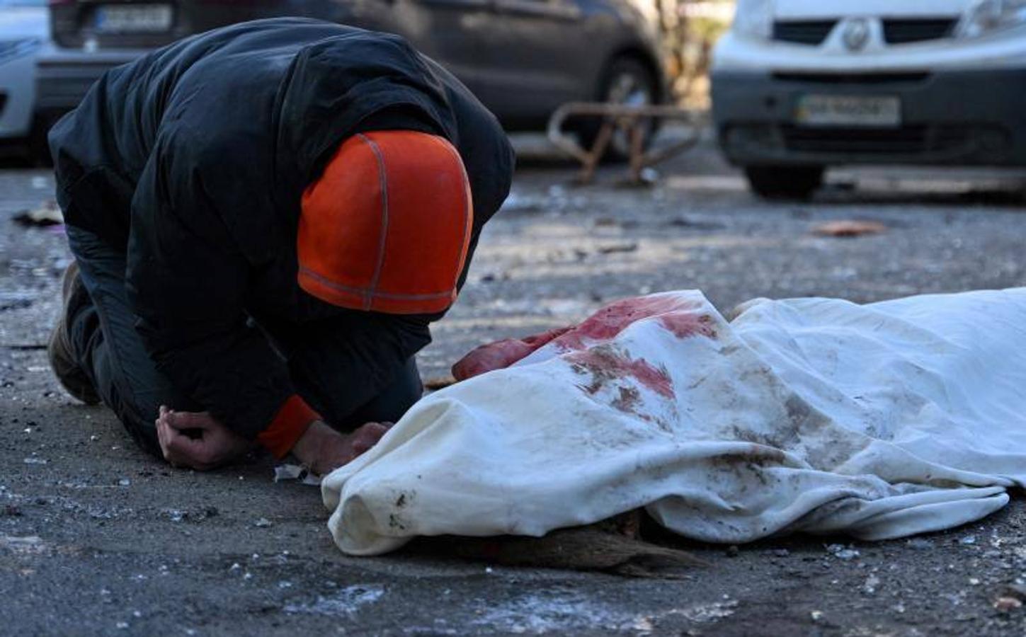 Una persona cerca de un cadáver en un edifico dañado en Kiev. 