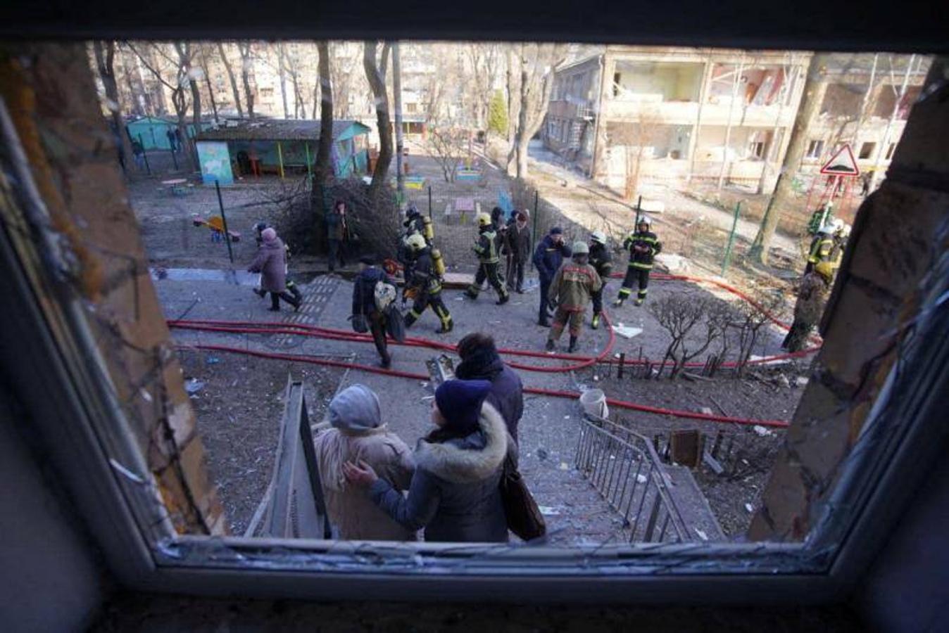 Personas se paran junto a un edificio residencial dañado por un bombardeo, mientras continúa el ataque de Rusia contra Ucrania, en Kiev.