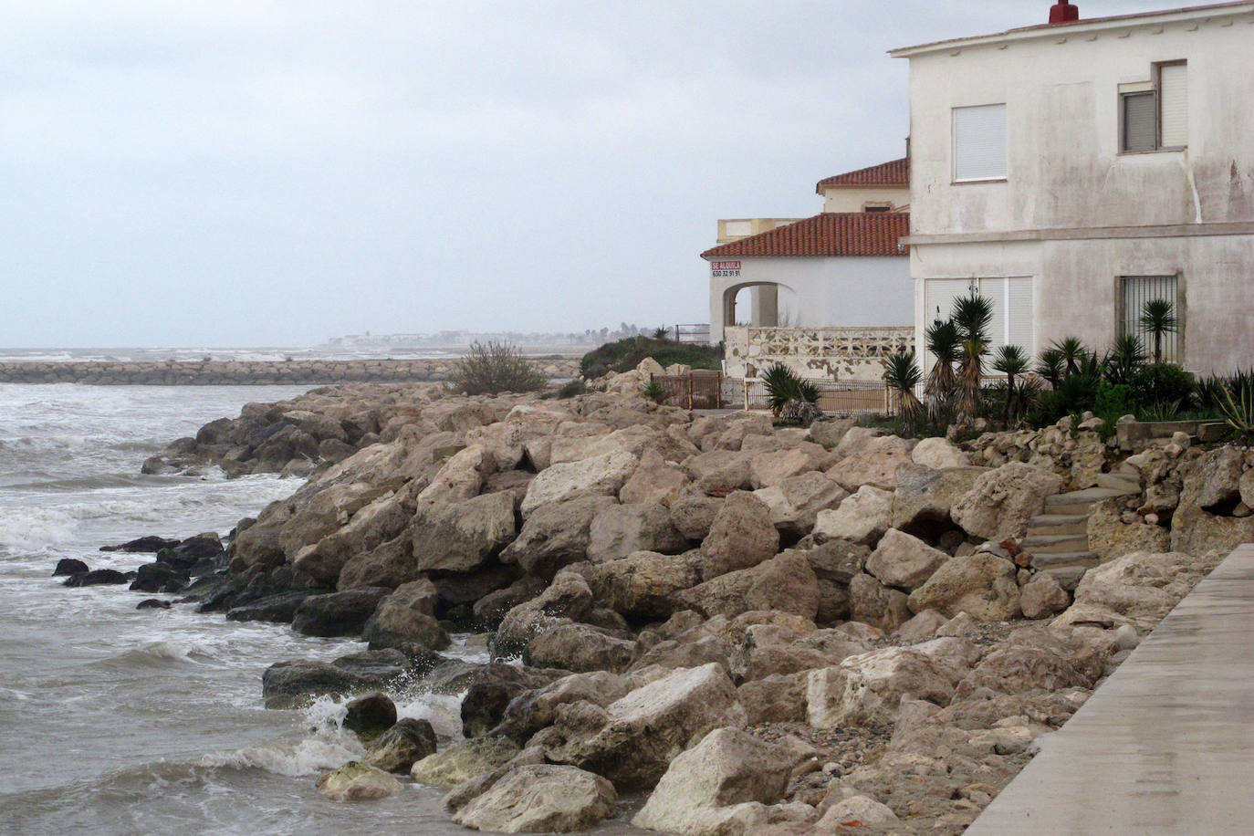 Playa de Les Deveses, con el mar llegando al muro de contención y casi sin tramo de arena por el oleaje y por elevarse el nivel del agua.