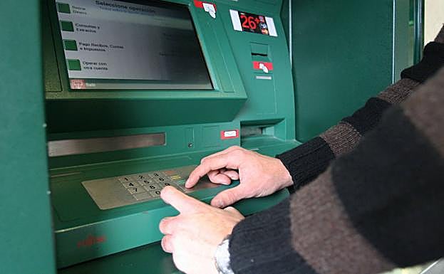 Un hombre usa un cajero. 
