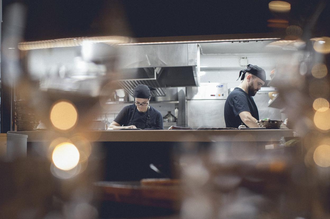 Encar y Alejandro en la cocina del restaurante. A la derecha, un plato de bacalao al pil-pil. lp