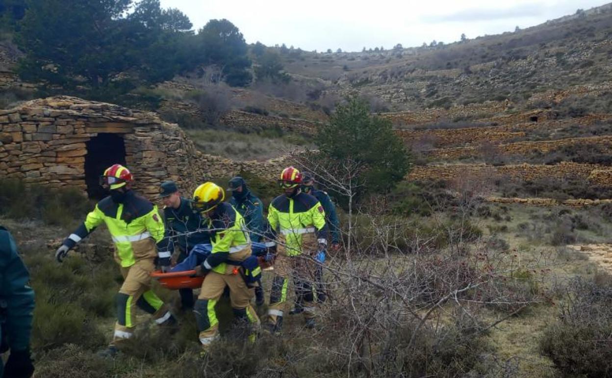 Agentes de la Guardia Civil y bomberos de la Diputación trasladan uno de los cadáveres. 