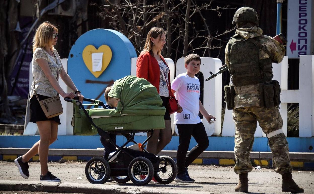 Un soldado ruso vigila una calle de la autoproclamada República Popular de Donetsk ante la mirada de una familia. 