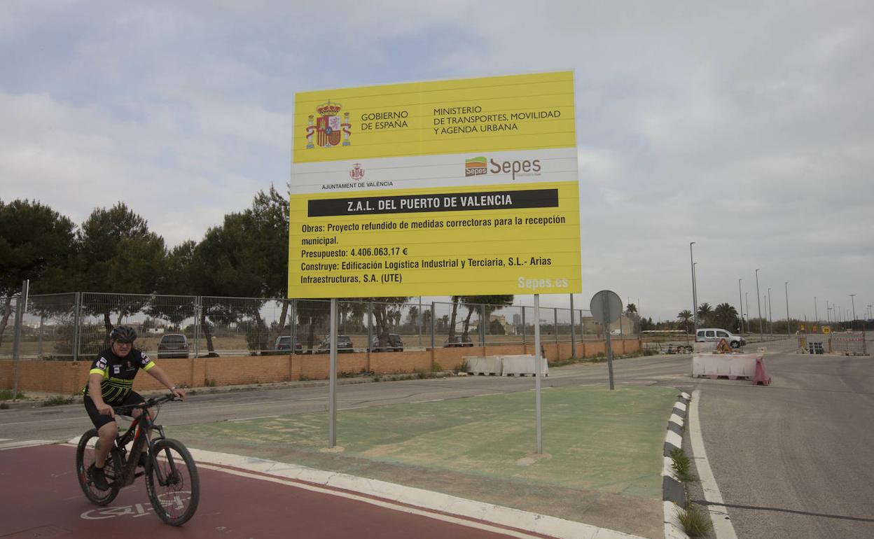 Un ciclista junto a uno de los carteles anunciadores de las obras de la ZAL. 