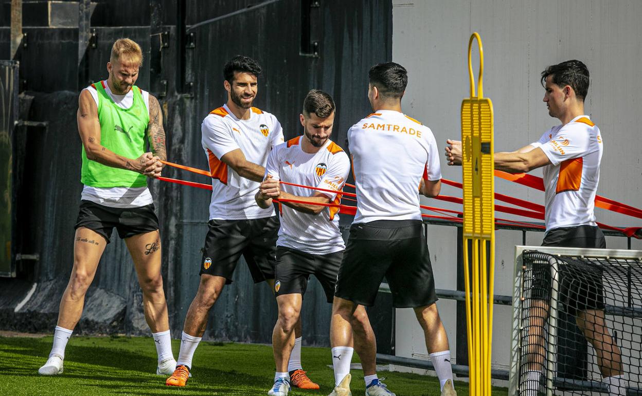 Los jugadores, haciendo ejercicios de fuerza con gomas en el entrenamiento de este martes. 