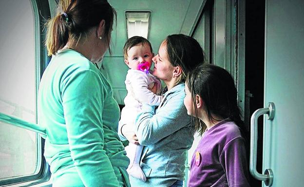 Vika abraza a su hija Carolina en el tren que les lleva de vuelta a Vinnytsia, después de dos meses acogidas por una familia polaca.