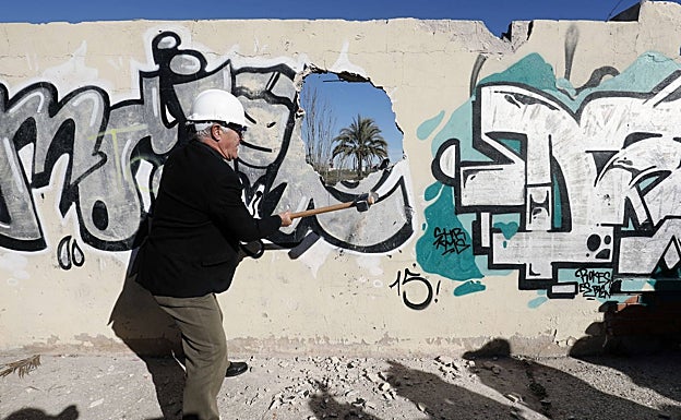 El alcalde de Valencia, Joan Ribó, dando un mazazo al muro que separa Nazaret del puerto en enero de 2019, en el parque pendiente de obras. 