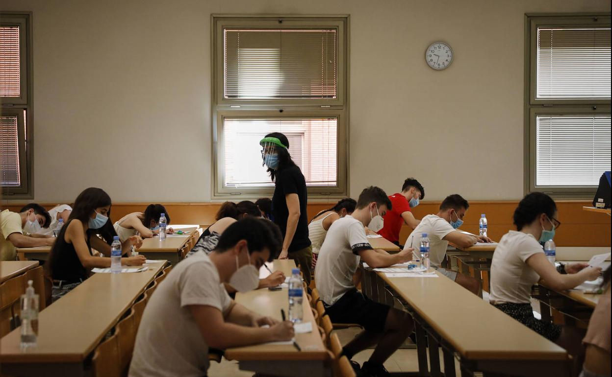 Un grupo de estudiantes realiza un examen con mascarilla. 