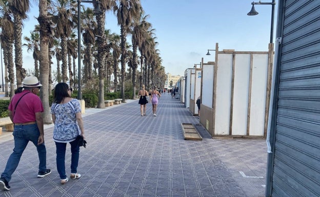 Paseantes siguiendo el proceso de montaje de los puestos de la playa del Cabanyal. 