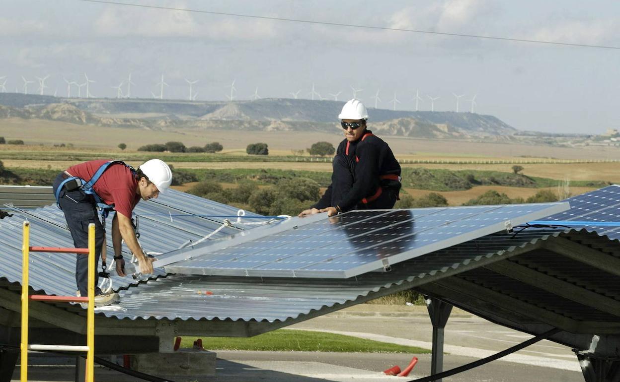 Dos trabajadores instalan placas solares. 