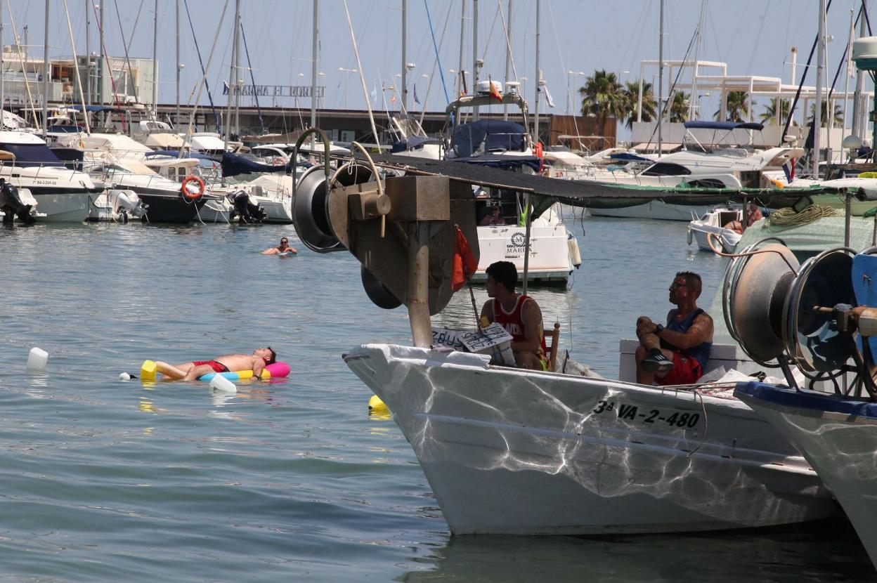 Varias personas tratan de encontrar alivio frente a las altas temperaturas en las aguas del Mediterráneo que bañan el puerto de Dénia. Tino CaLVO