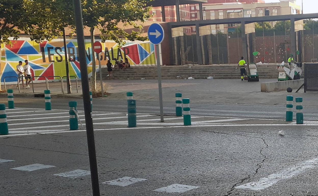 Operarios de limpieza, retirando los restos de un botellón en la puerta del instituto Benicalap. 