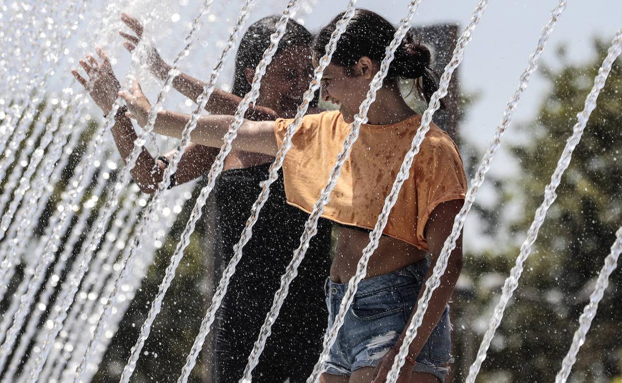 Dos jóvenes se refrescan en una fuente. 