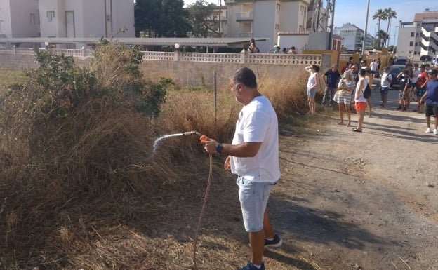 Un vecino remojando la vegetación cercana con su manguera para evitar que se prendiera. 