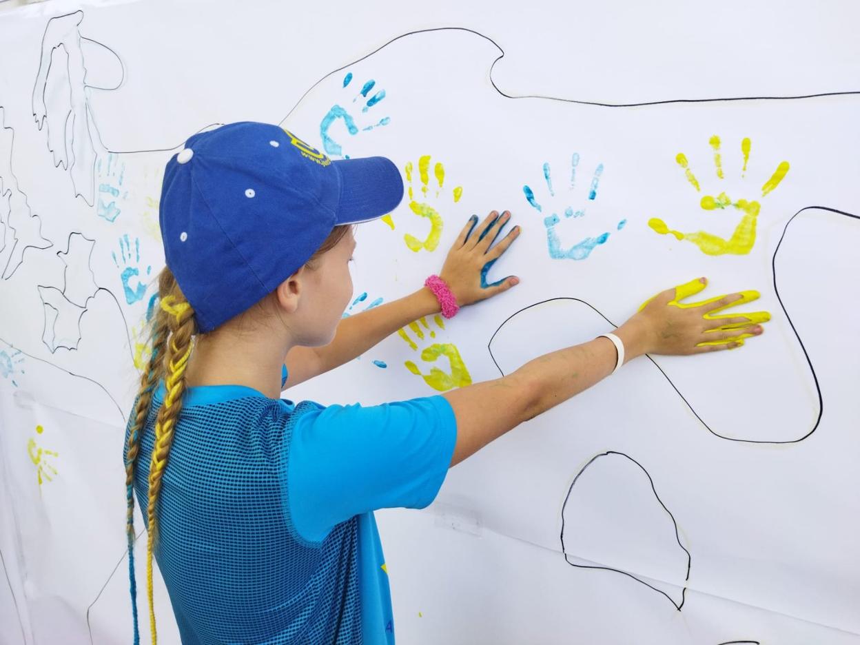 Una menor coloca sus manos con pintura en el mural en el colegio San Vicente Ferrer. benito pajares
