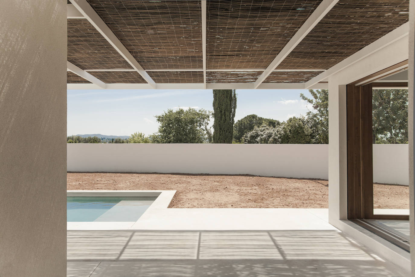 Un porche crea una zona de sombra junto a la piscina.