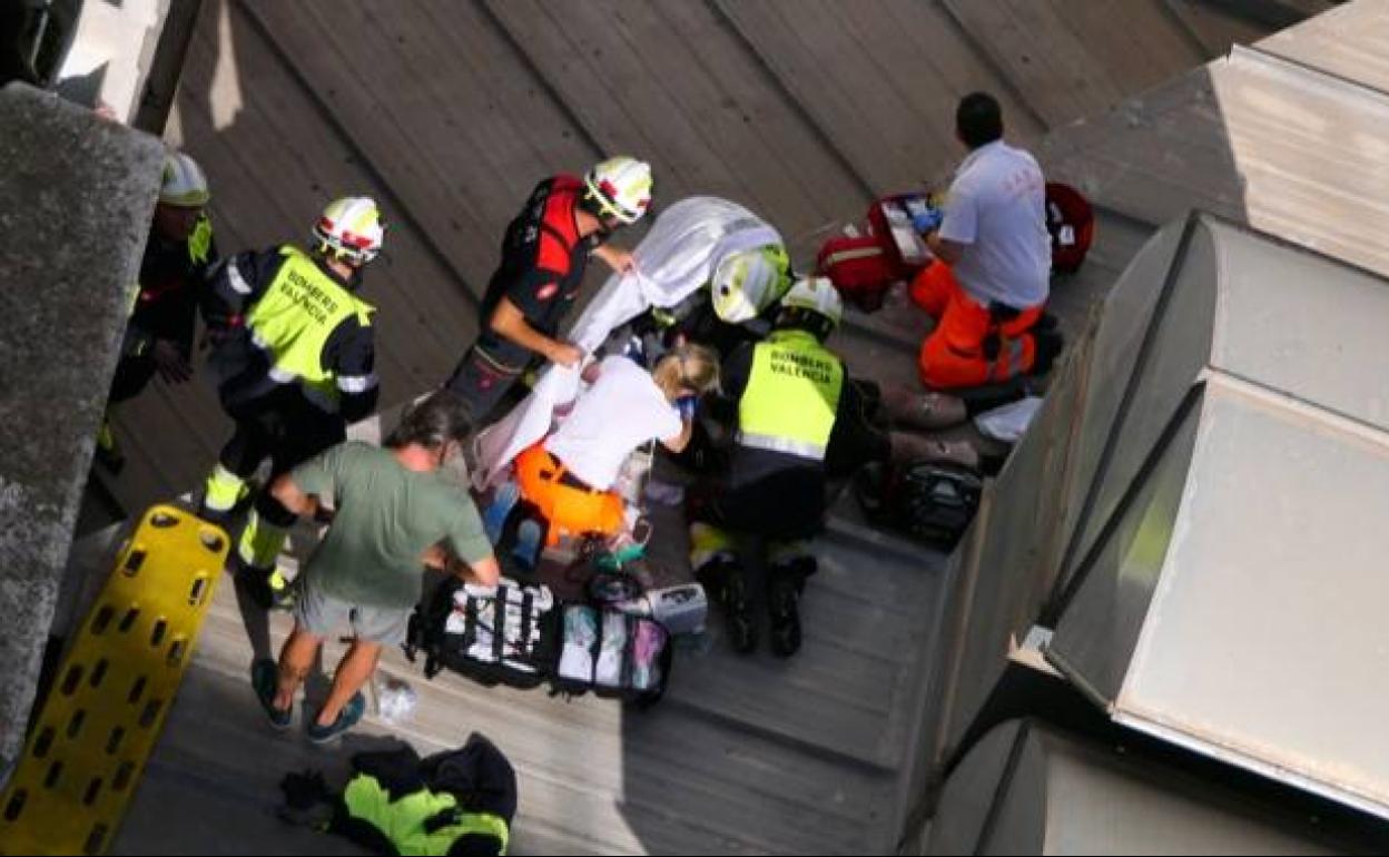 Bomberos y personal sanitario auxilian a la víctima, esta mañana, en la calle Cuenca. 