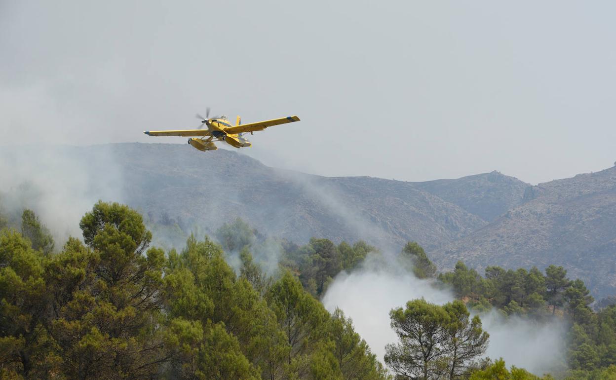 Un avión lanza agua en las llamas del incendio de Vall d'Ebo. 