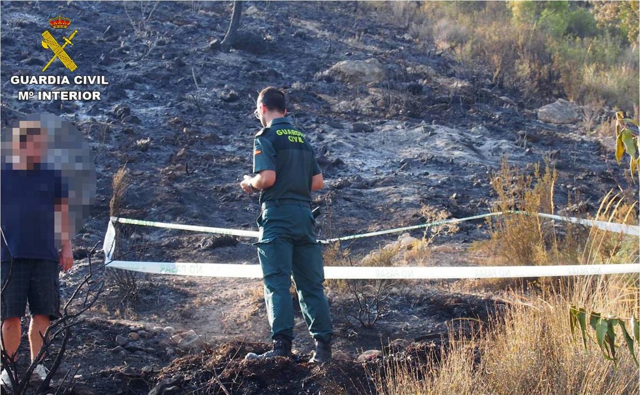 Un guardia civil inspecciona el terreno donde se habría originado el incendio. 