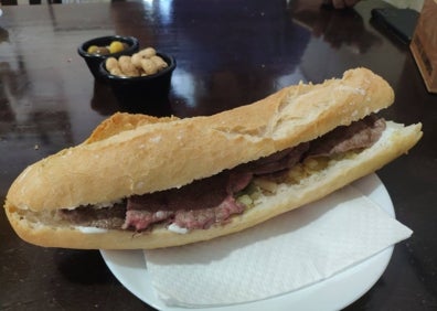 Imagen secundaria 1 - Arriba, local del bar Júcar, lleno de fotografías de clientes. Abajo, el bocadillo de la casa, con entrecot, allioli casero, ajos tiernos y patatas a la pobre. A la derecha, bocadillo Marinero, con titaina y huevo frito.