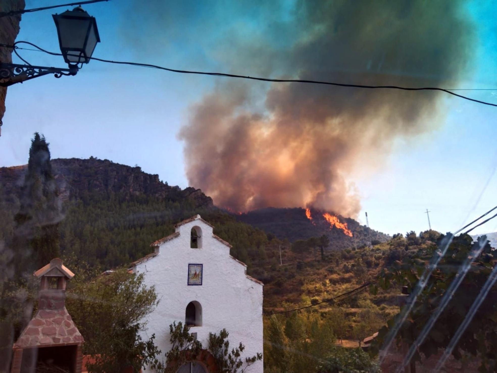 El fuego avanza. Las llamas alcanzaron la aldea y un árbol que se estaba quemando comenzó el incendio en el tejado de la ermita. Lp