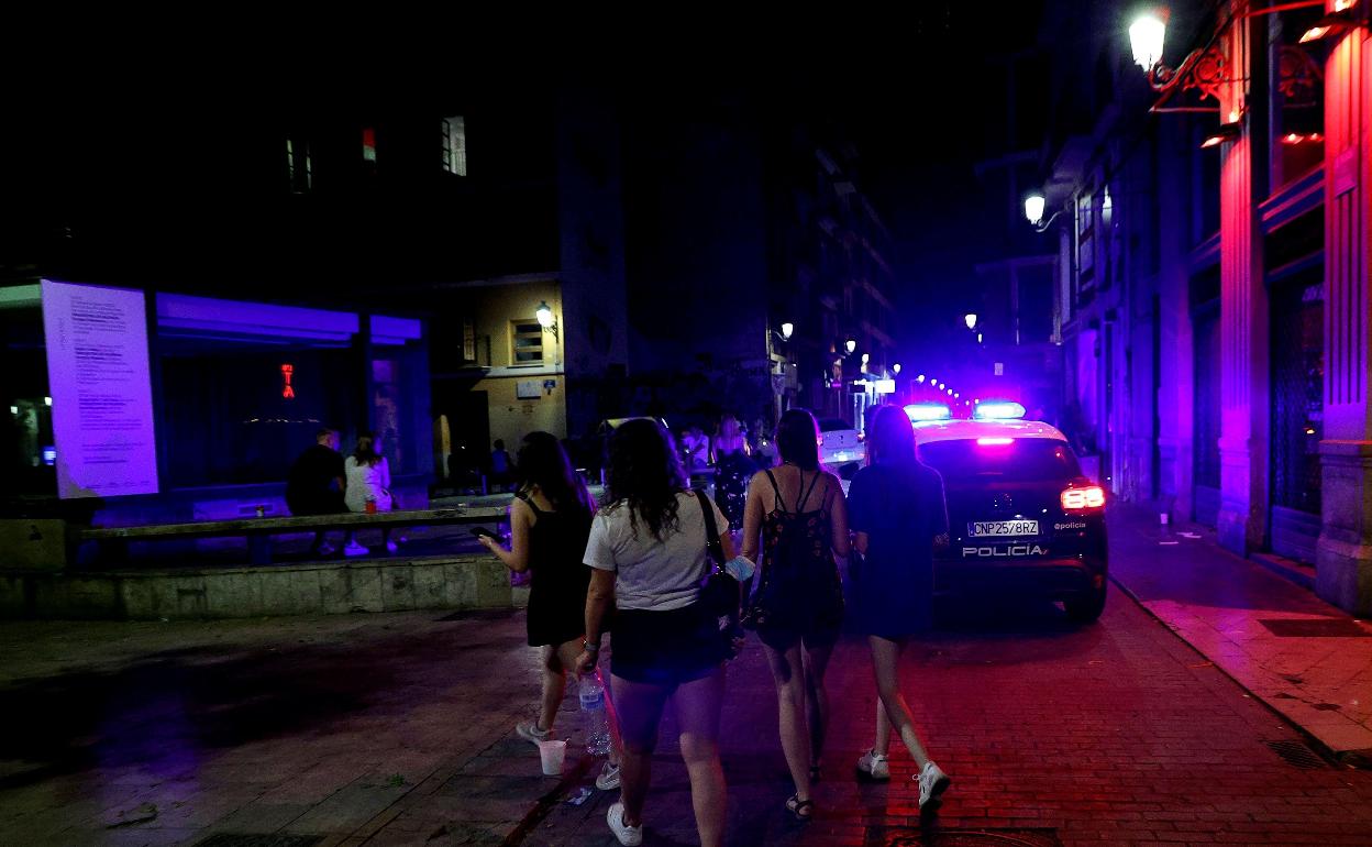 Varias jóvenes pasan ante una patrulla policial en la calle Caballeros de Valencia. 