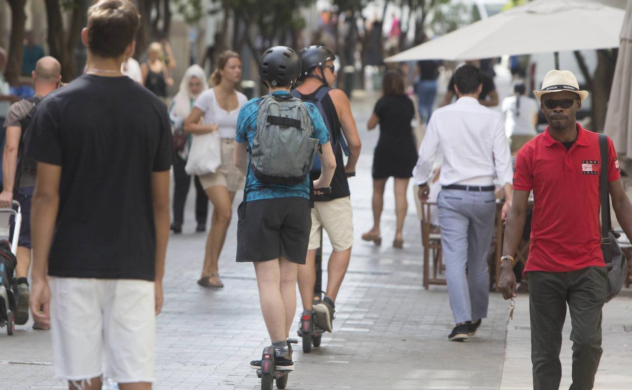 Usuarios de patinetes en una calle peatonal en Valencia. 