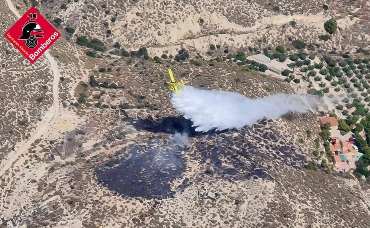 Una avioneta descarga agua sobre la superficie calcinada, este domingo en Aigües.  