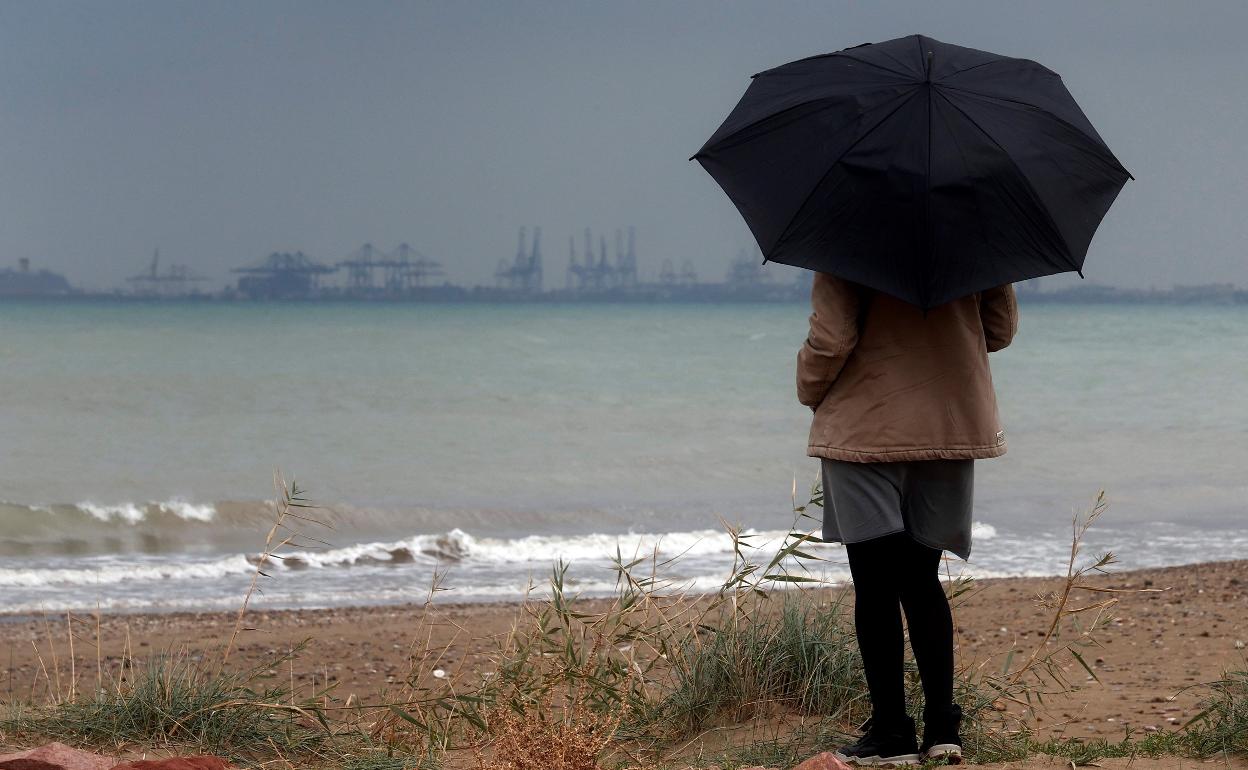 Una mujer contempla el mar durante un episodio de lluvias. 