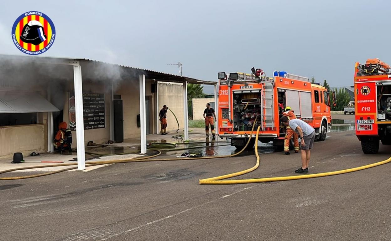 Los bomberos sofocan el fuego que se producía en un almacén junto al campo de fútbol. 