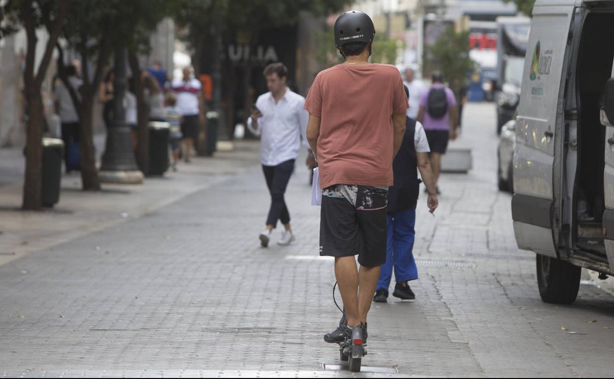 Un joven en patinete por una calle de Valencia. 