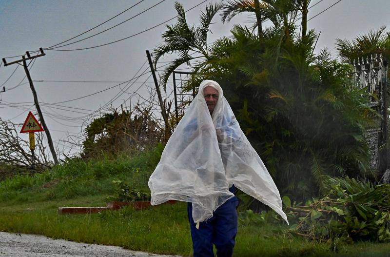 Un hombre se protege de la lluvia en San Juan y Martínez, en la provincia de Pinar del Río, al occidente de la isla, la zona más afectada por el paso de Ian.