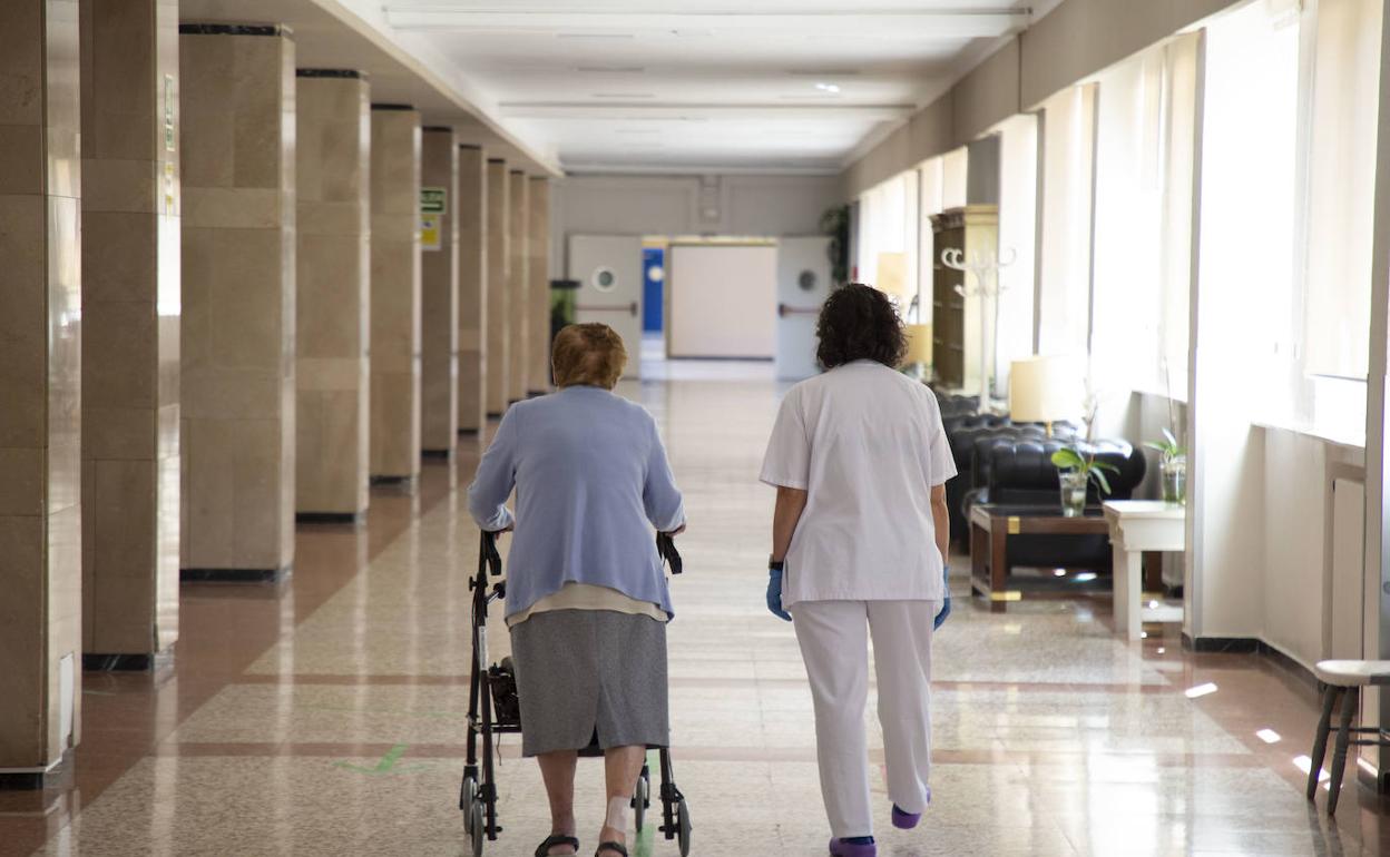 Una anciana junto a una trabajadora en una residencia. 